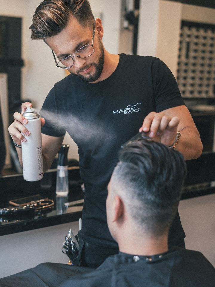 A barber spraying a fresh taper