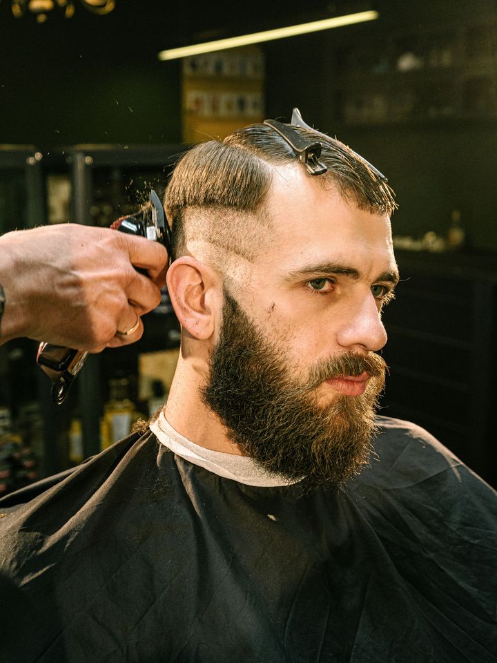 A barber blending a fade into a full beard