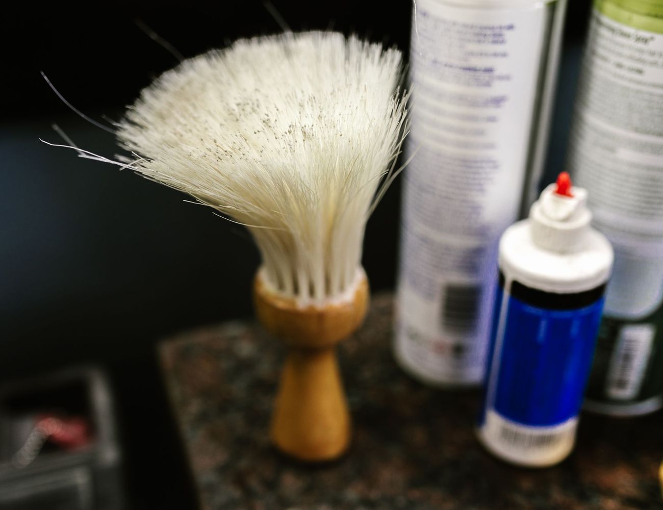 A shaving brush and styling products on the counter