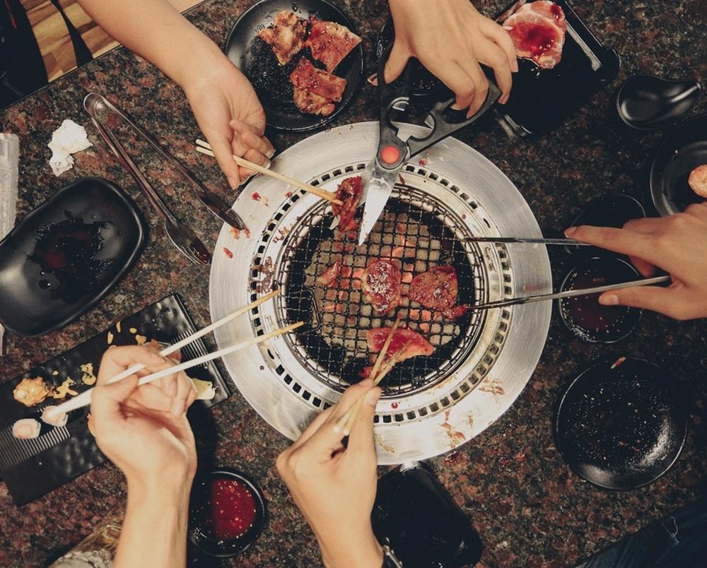 Friends grilling around a round charcoal grill