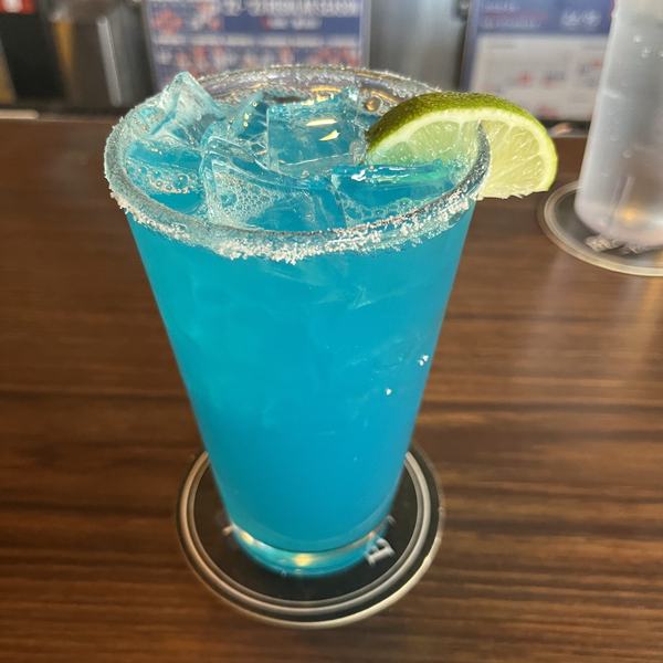 A blue margarita with a lime wedge