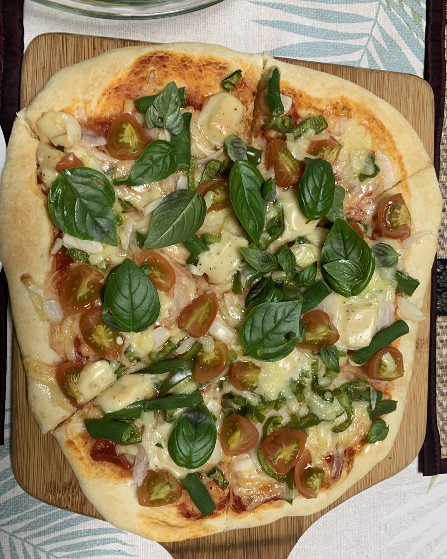A pizza with basil and cherry tomatoes on a board