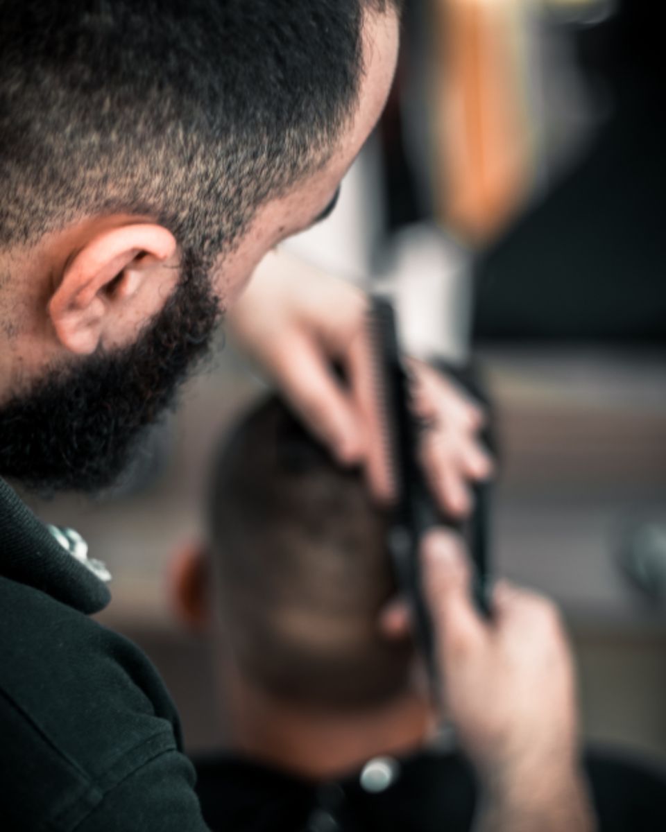 A barber taking a fade up the back of a client’s head with clippers
