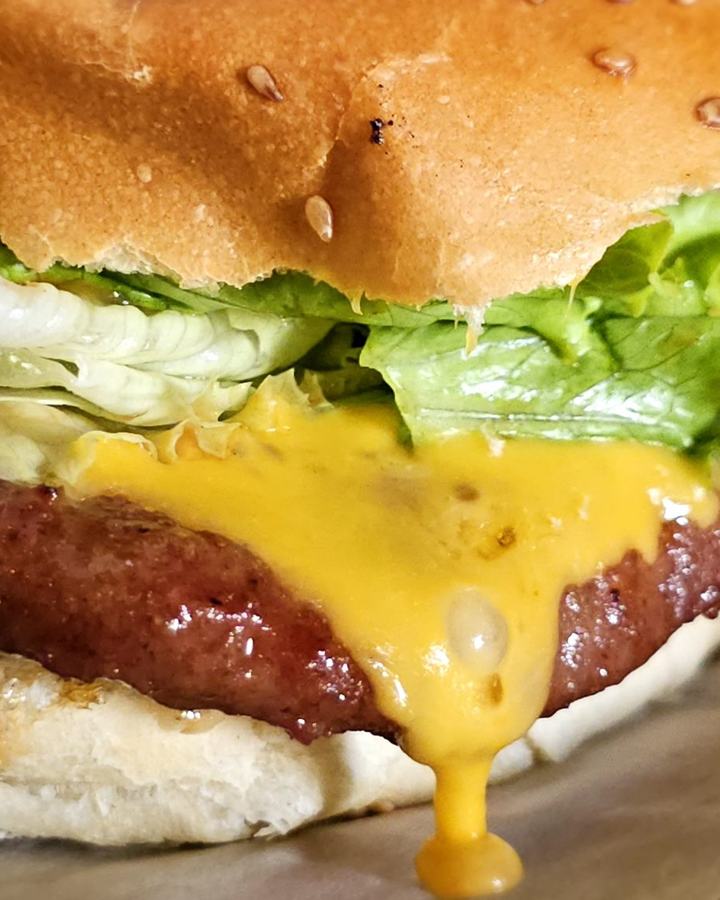 A burger with melted cheese running down the patty