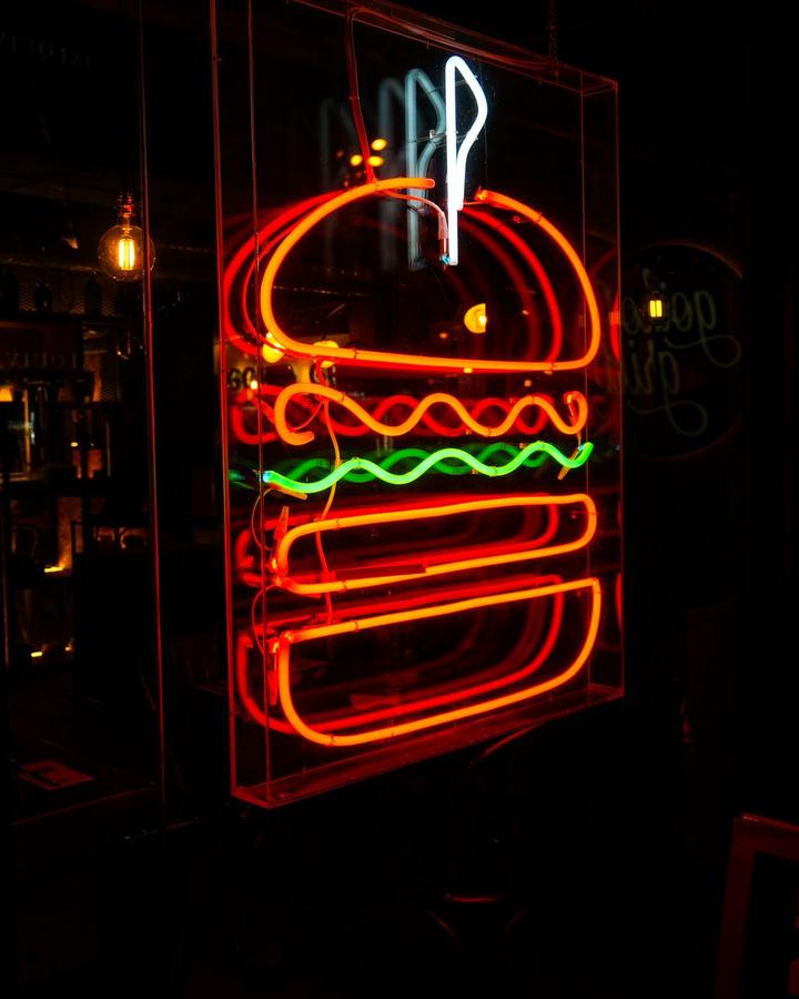 A neon burger sign glowing in the dark